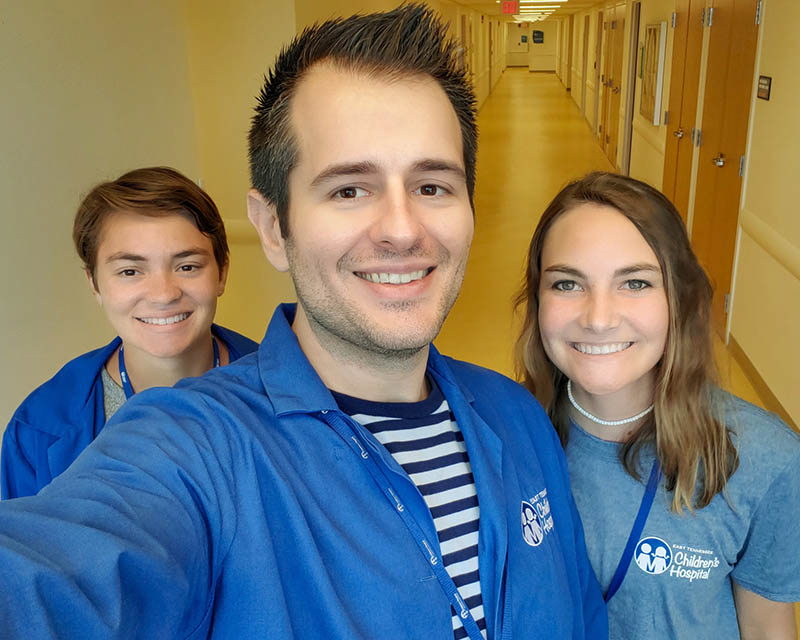 Selfie of Michael in a hospital hallway flanked by two volunteers