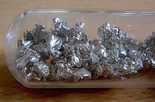Crystals of silvery calcium metal in a glass vial