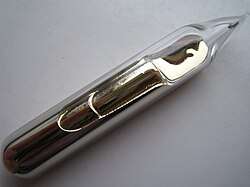 Some pale gold metal, with a liquid-like texture and lustre, sealed in a glass ampoule