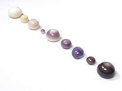 A collection of natural quahog pearls ranging from white to dark purple.