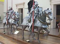 Three statues of riders and horses in armour