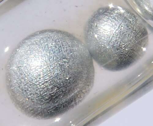 Two spherical beads of potassium metal in a container filled with oil
