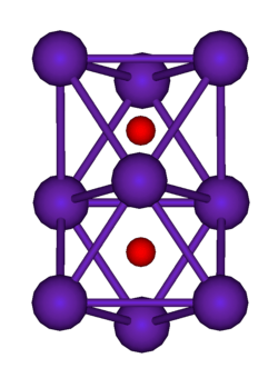 The ball-and-stick diagram shows two regular octahedra which are connected to each other by one face. All nine vertices of the structure are purple spheres representing rubidium, and at the centre of each octahedron is a small red sphere representing oxygen.