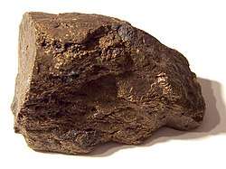 A brown block of irregular shape and surface, about 6 cm in size.