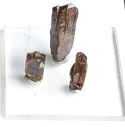 Three column shaped brown crystals on a white background