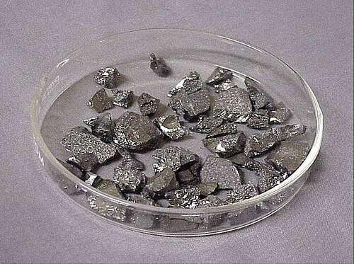 Small chips of lustrous gray metal in a glass dish